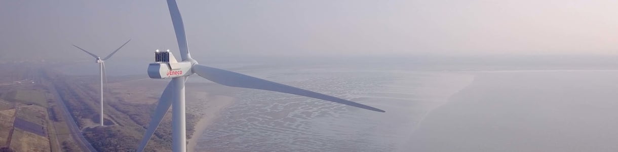Een windturbine van Eneco in een kustomgeving, wat wijst op duurzame energieproductie uit windenergie.