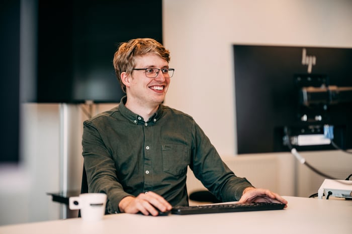 Een lachende man achter een computer