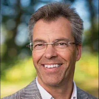 Lachende man met bril in grijs pak in de natuur