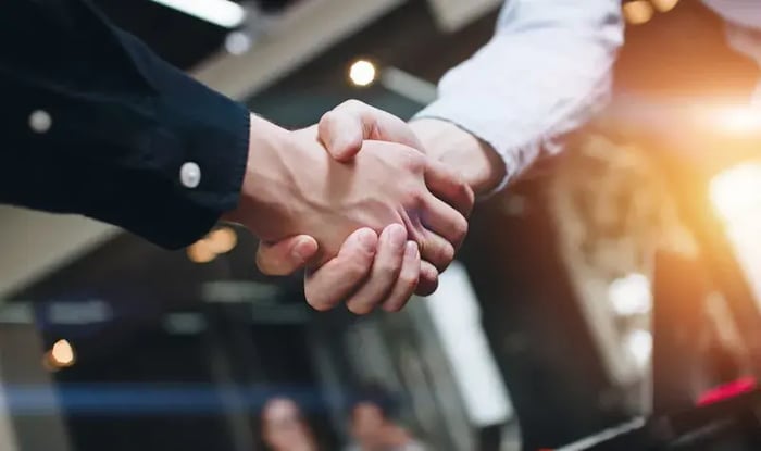 Twee collega's schudden elkaar de hand.