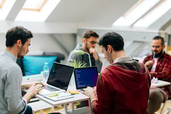 Mannen die achter laptops werken