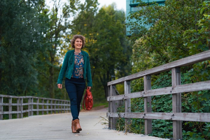 Een lachende vrouw die over een houten brug wandelt