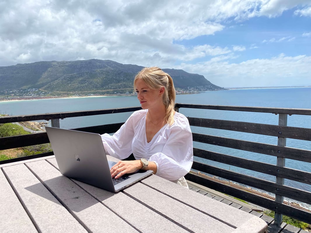 Woman sitting behind a laptop on a sunny balcony