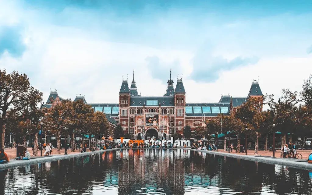 Het Rijksmuseum in Amsterdam weerspiegeld in de vijver met de stad op de achtergrond.