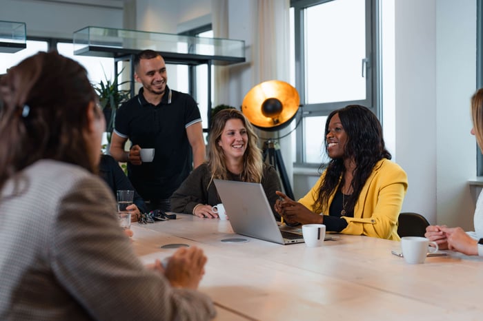 vrouwen achter computer met collega's staand