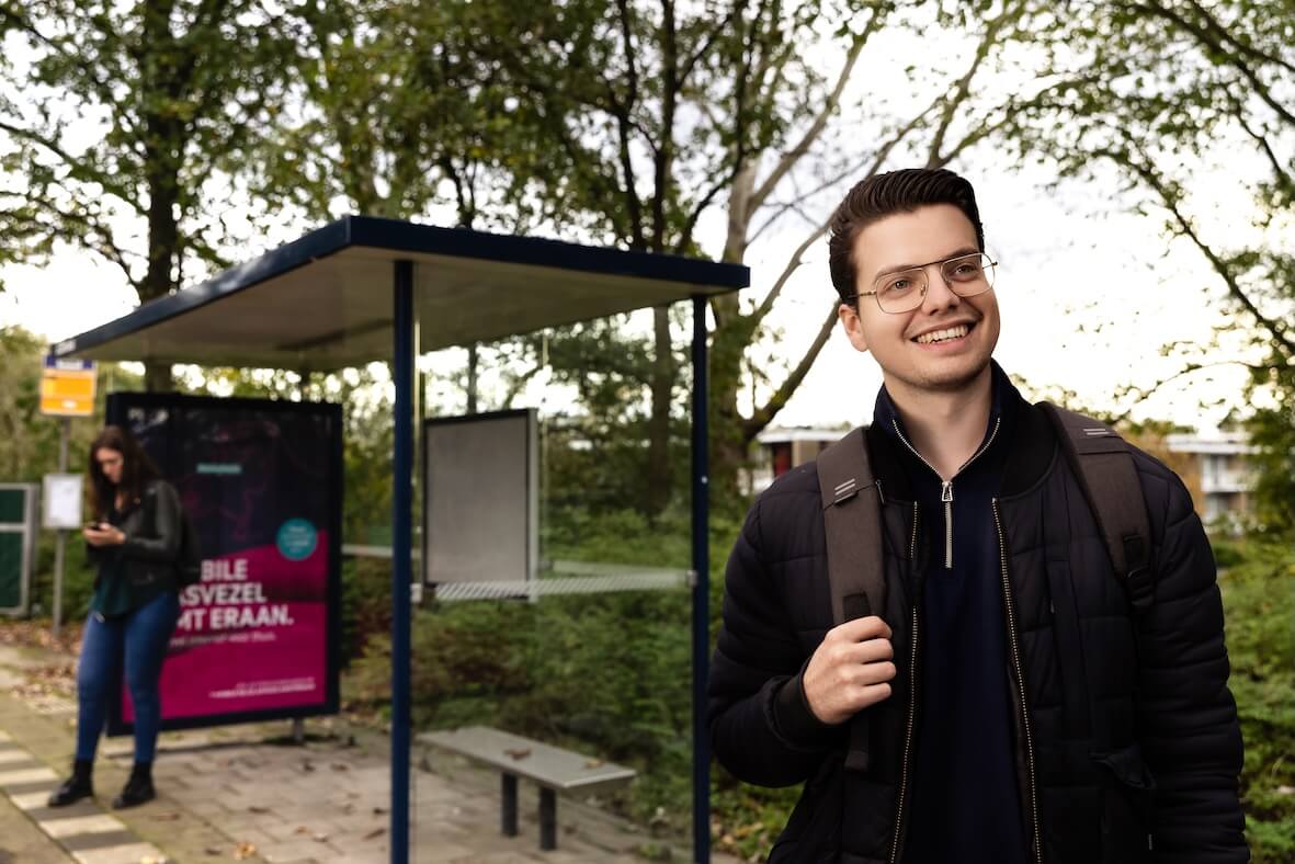 Mannelijke reiziger wacht bij een bushalte.