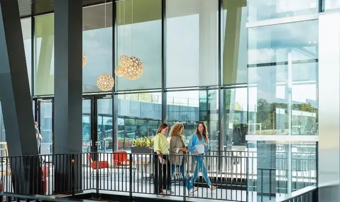 Droe mensen lopend in een hal van een kantoor