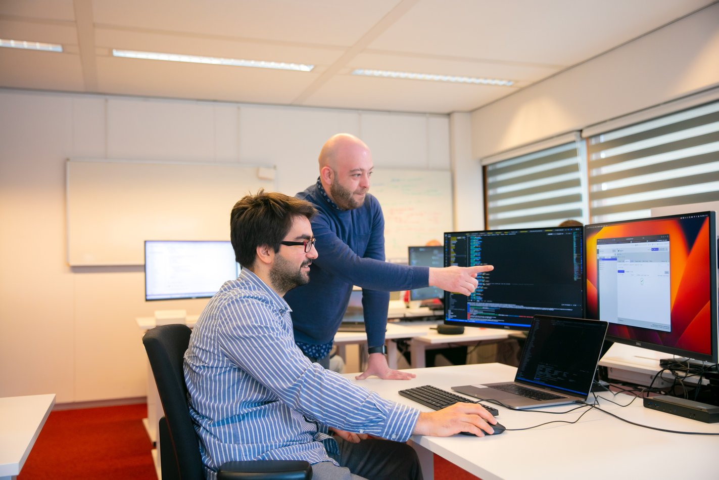 Twee collega’s werken samen achter een computer op kantoor.