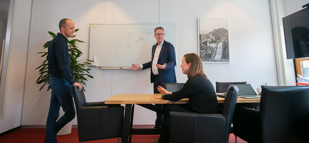 Drie mensen in een kantoorruimte die overleggen