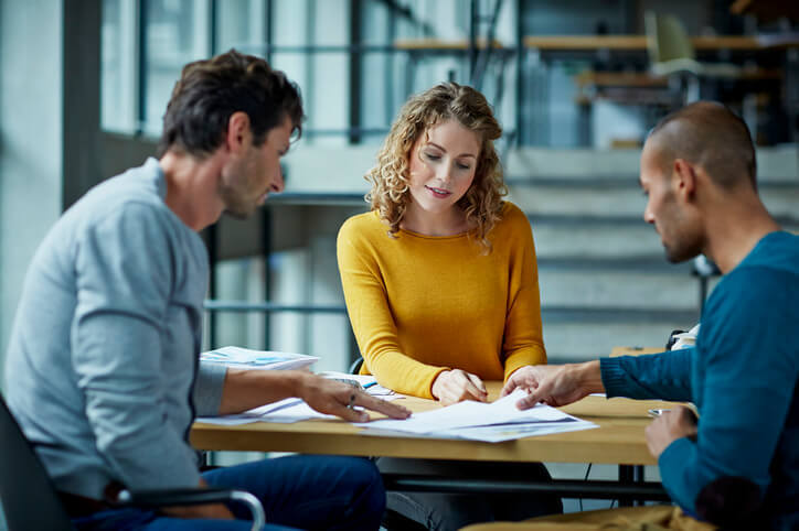 Twee mannen en een vrouw azitten aan een tafel