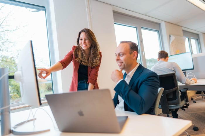 Male and female colleague behind a computer screen.