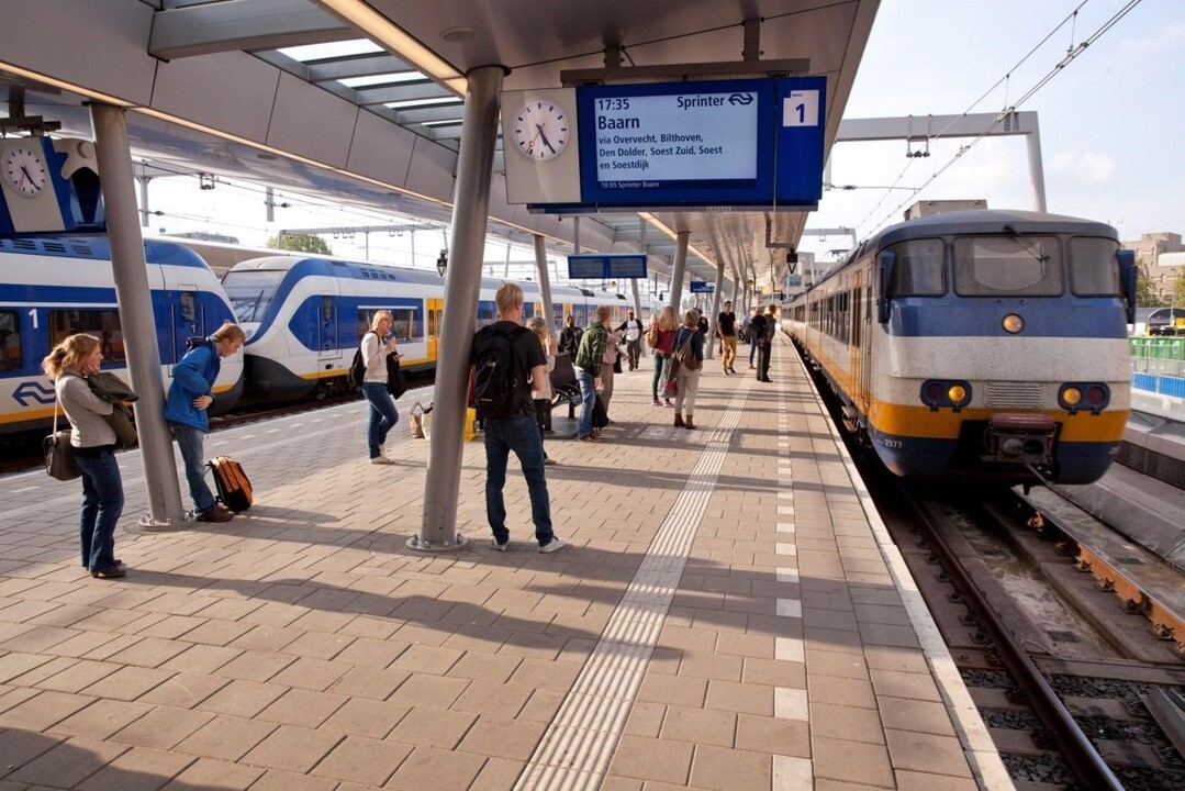 NS-station met reizigers en een Sprinter naar Baarn.
