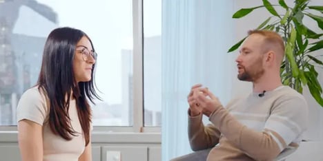 A dark hair woman with glasses and a blond man with a beard, talking to each other