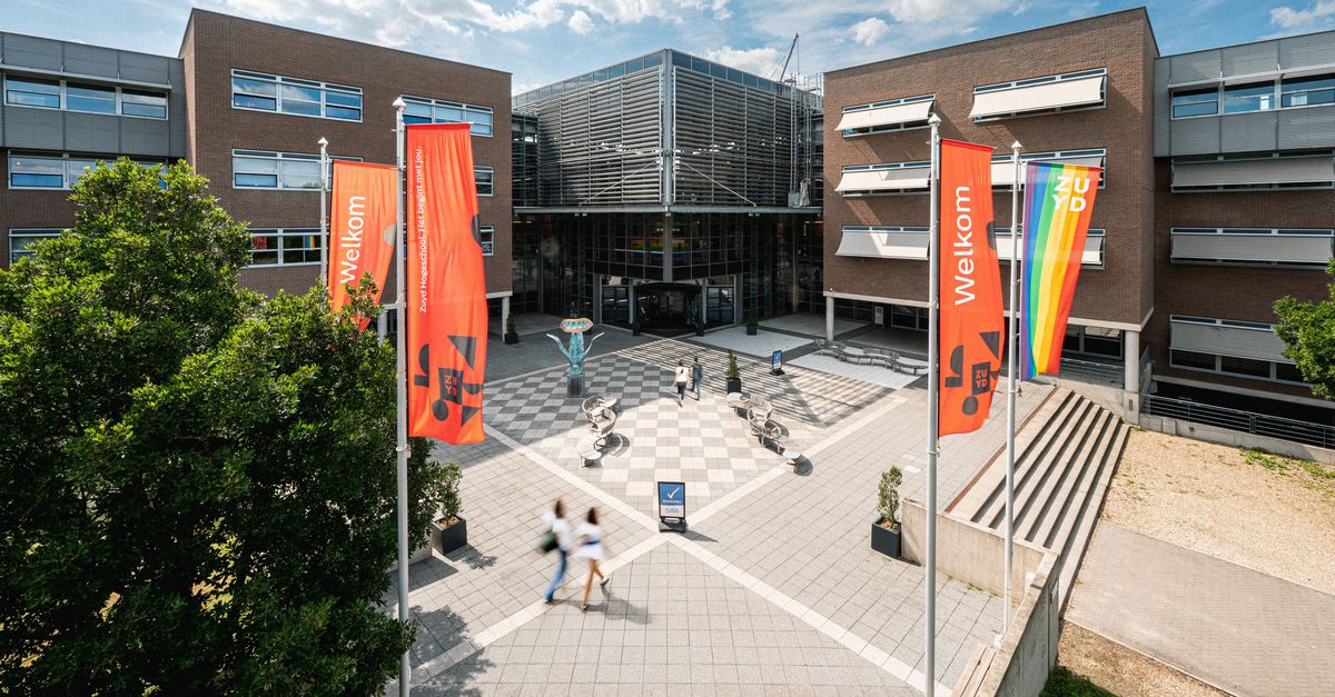 Gebouw van Zuyd Hogeschool met rode banners, mensen lopen op de campus.