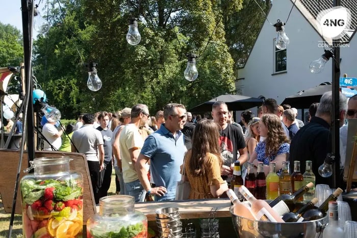 Mensen netwerken buiten op een zonnig evenement, met drankjes op de voorgrond.