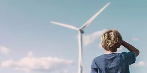Jong jongetje kijkt naar een windmolen in de verte