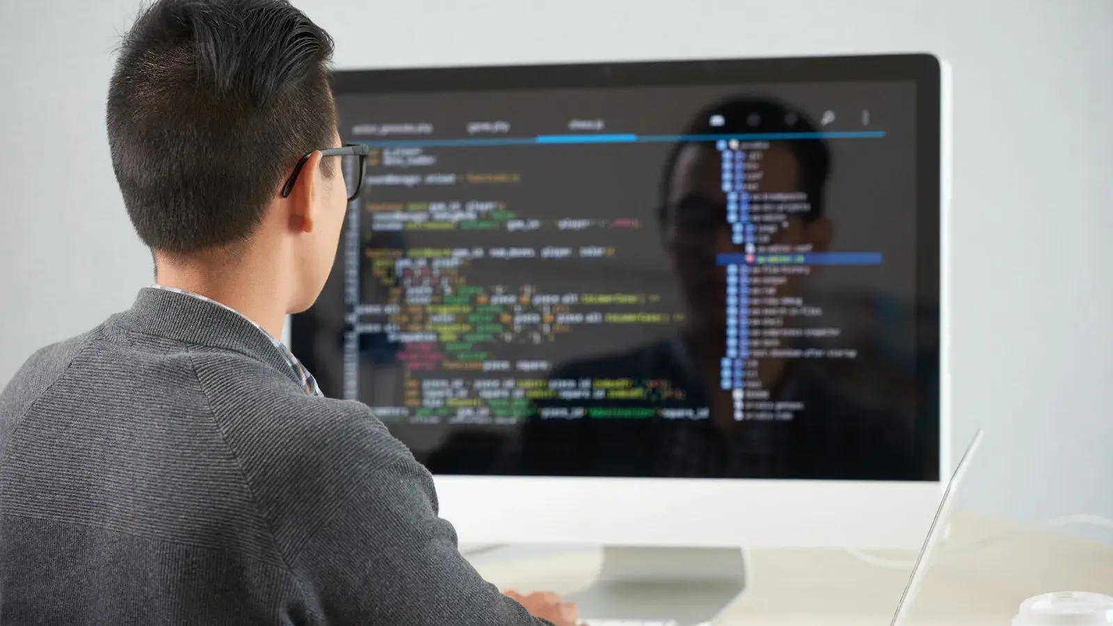 Man met bril bekijkt data gegevens op groot beeldscherm