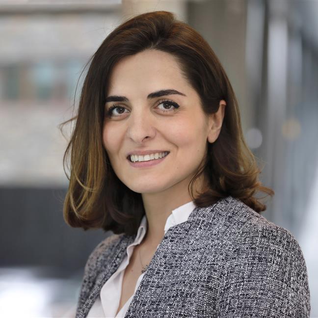 Vrouwelijke collega kijkt vriendelijk de camera in.