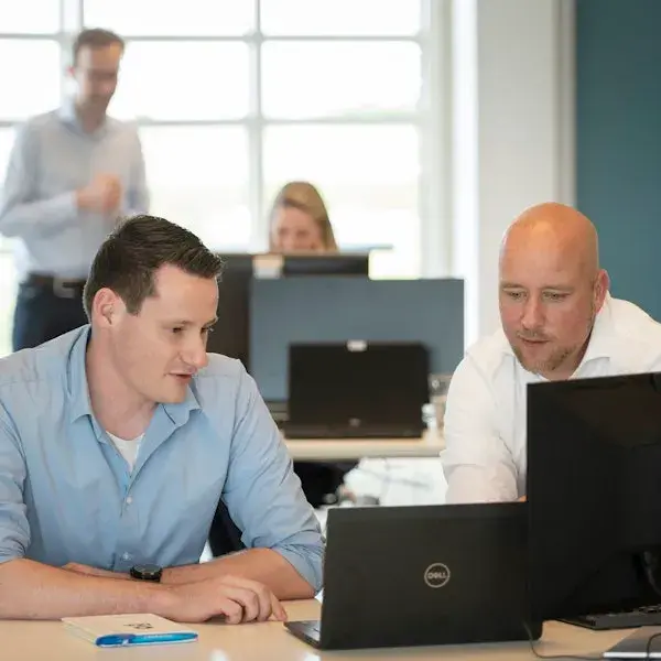 Twee collega's kijken aandachtig naar computerscherm.
