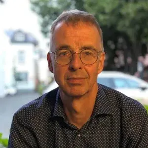 Man met bril glimlacht naar de camera.