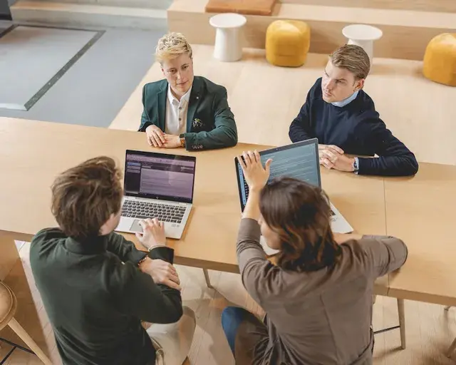 vier mensen aan tafel aan het overleggen