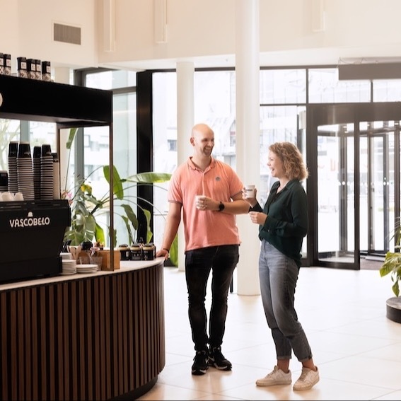 Collega's drinken koffie in de hal van een gebouw.