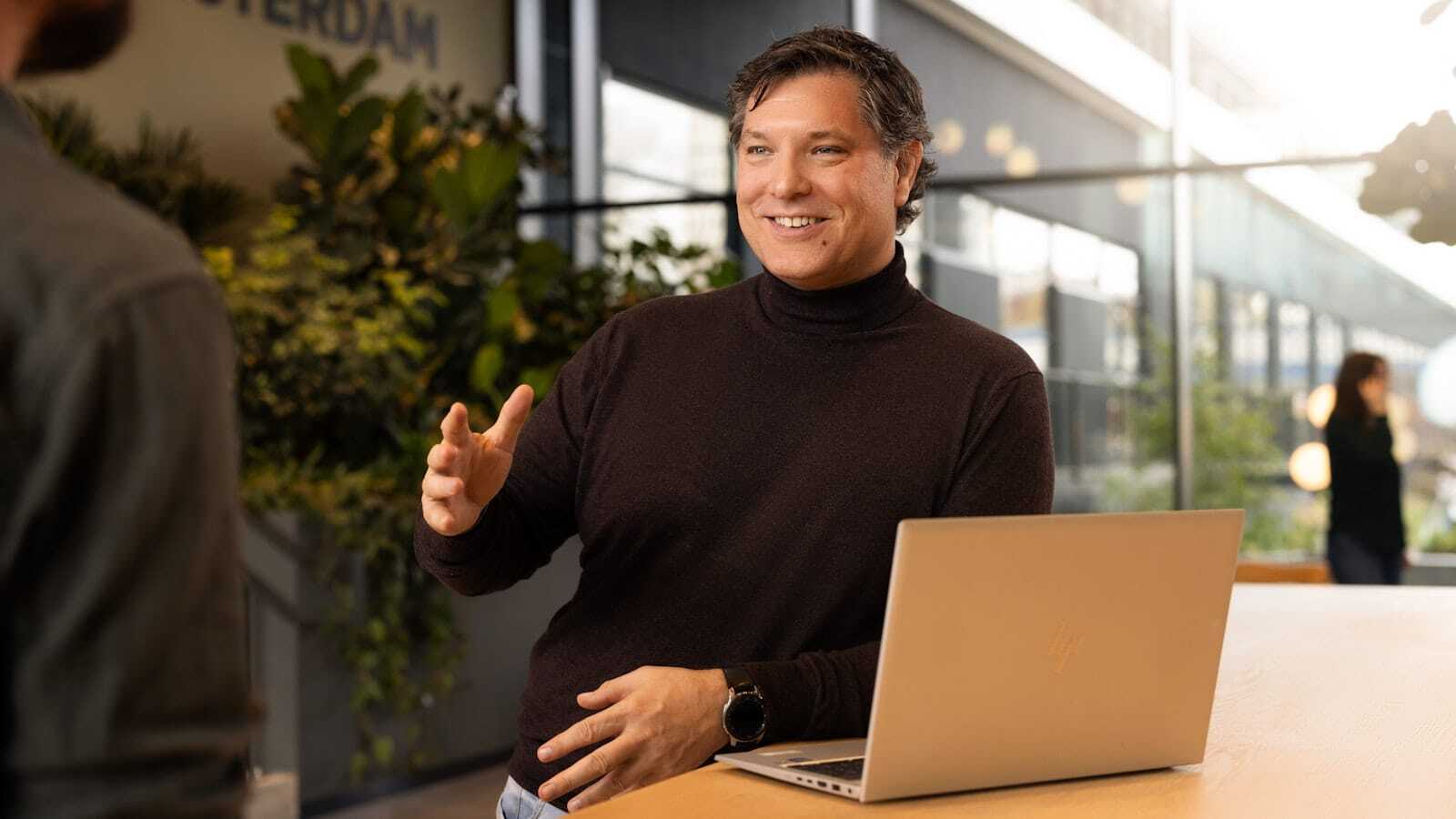 Mannelijke collega met laptop rijkt zijn hand uit.