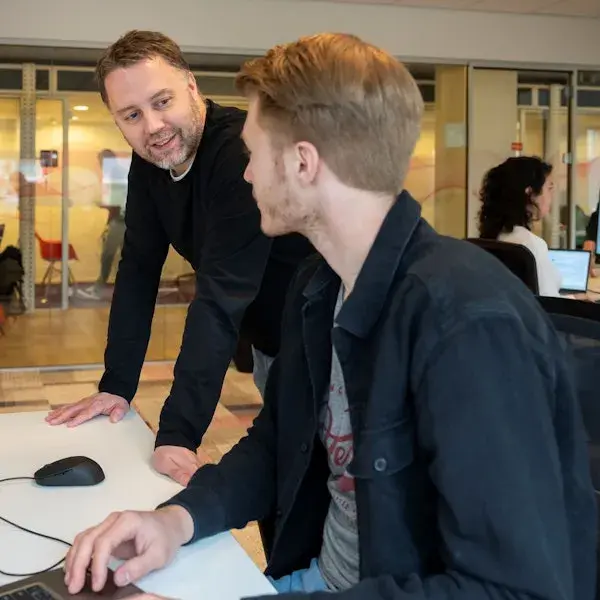 Twee mannelijke collega's achter een computer.