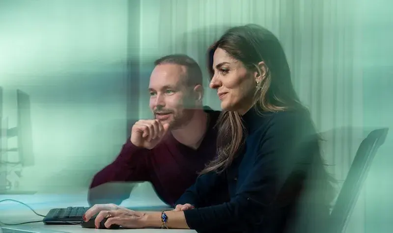 Twee collegas kijken naar een scherm