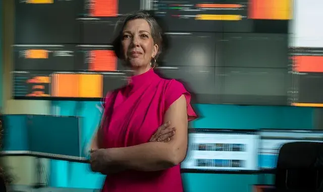 vrouw kijkt blij in de camera met wazige ict beelden op achtergrond