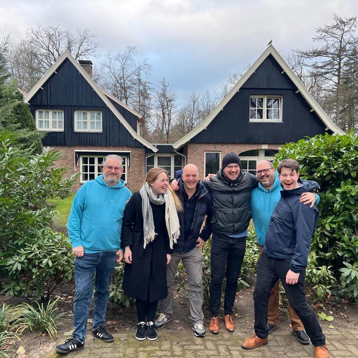 Collega's in jassen voor een huisje in de natuur,