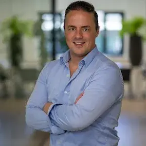 Een man met zijn armen over elkaar die glimlacht