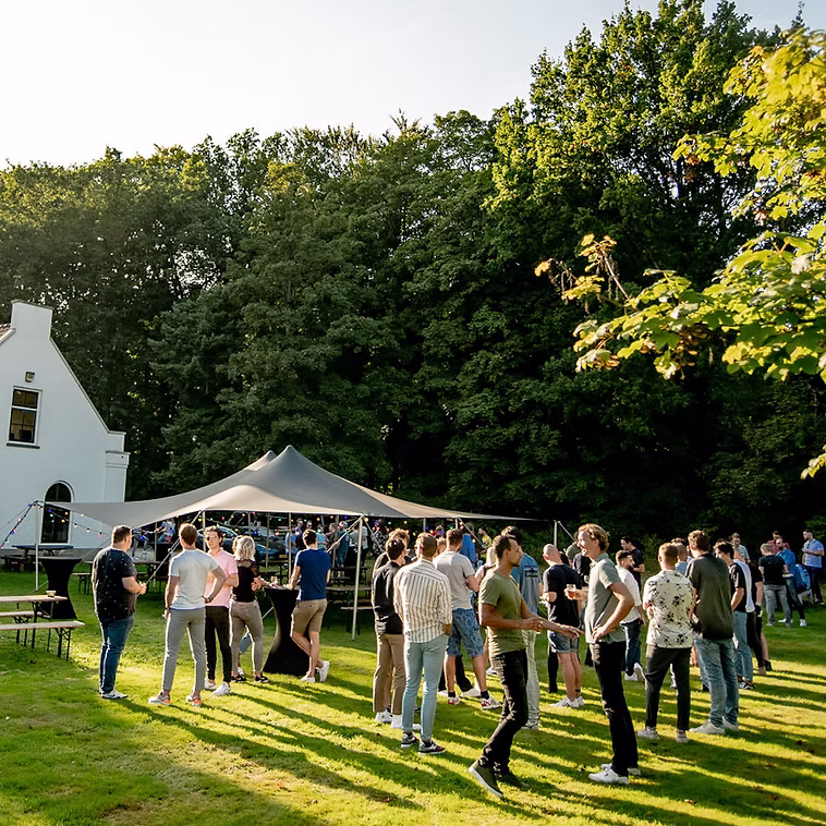 Mensen netwerken buiten op een grasveld tijdens een zomeravondevenement.