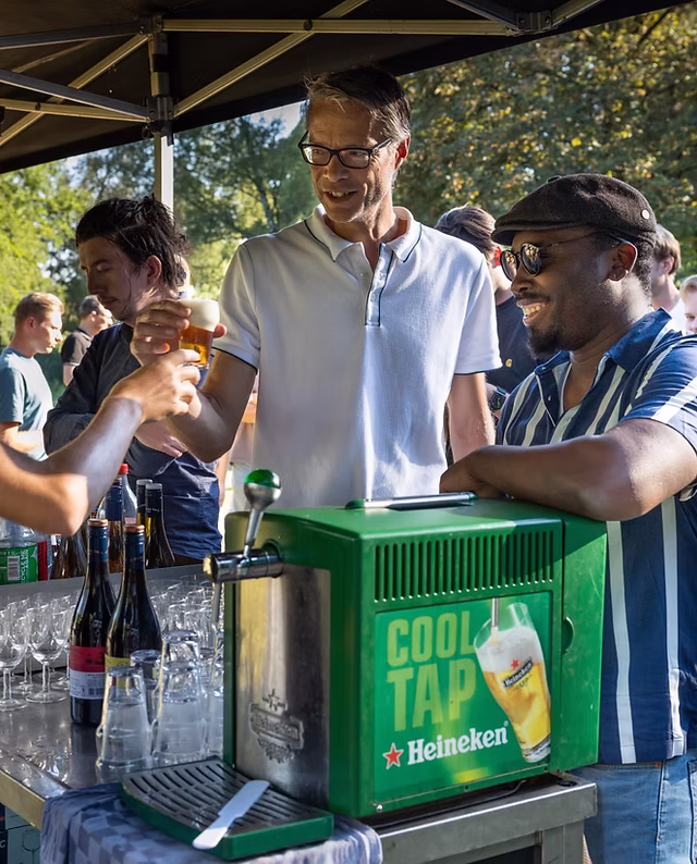 Mannen tappen en proosten bij een Heineken Cool Tap op een buiten-evenement.